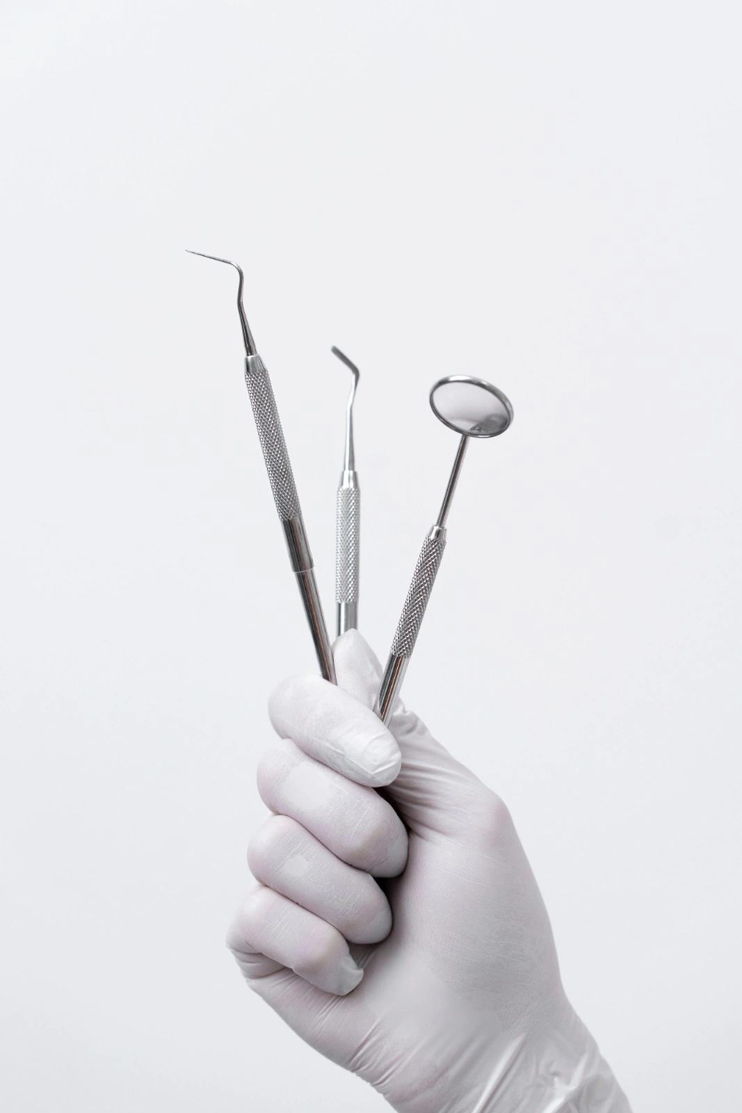 Gloved hand holding dental instruments